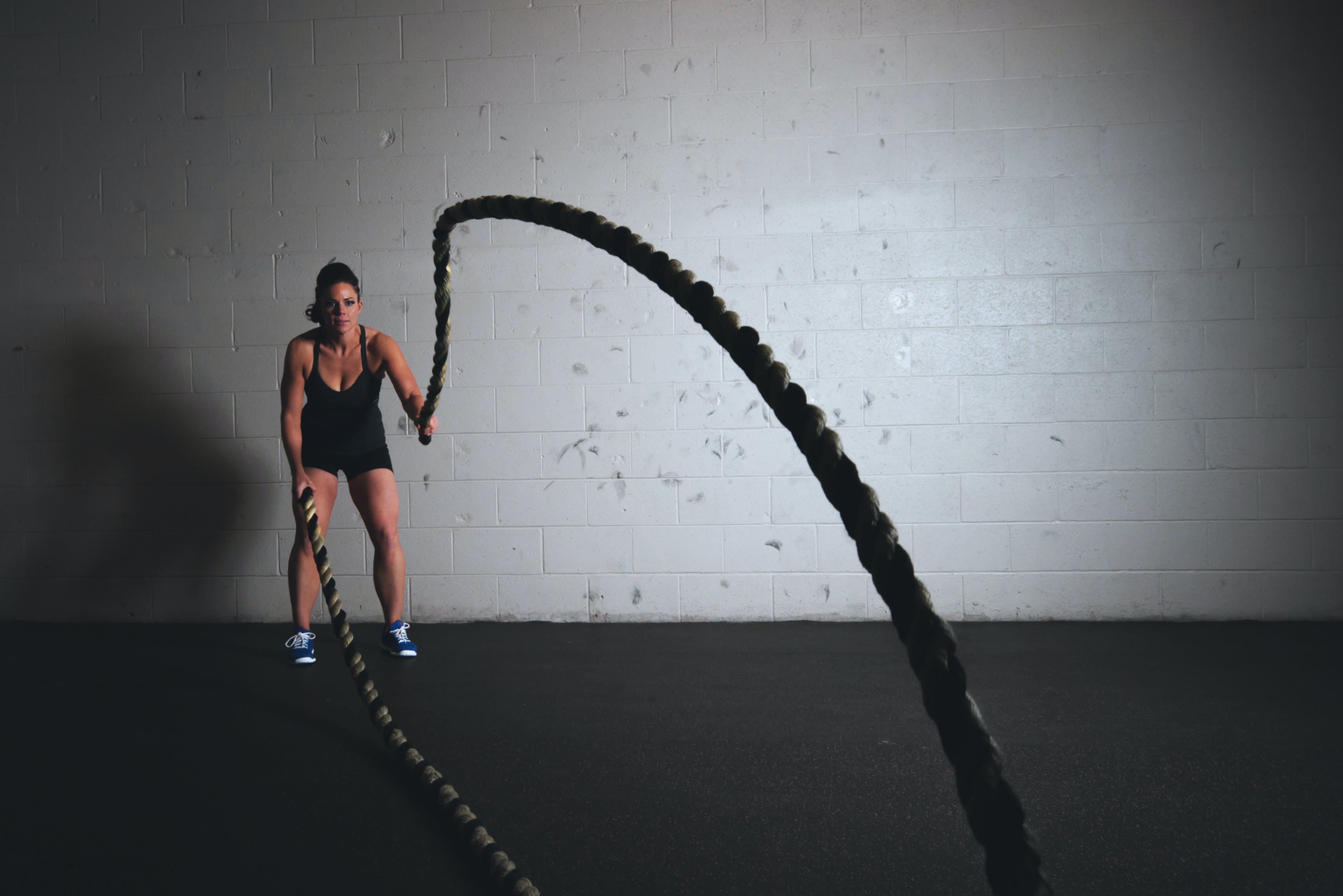 A strong woman working out with battle ropes.